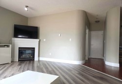 Living area featuring a white mantel fireplace, wood-finish flooring, and a curved wall architectural detail - 