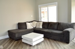 Spacious living area featuring wood-finish flooring, neutral wall tones, and a sliding glass door leading to an outdoor balcony - 