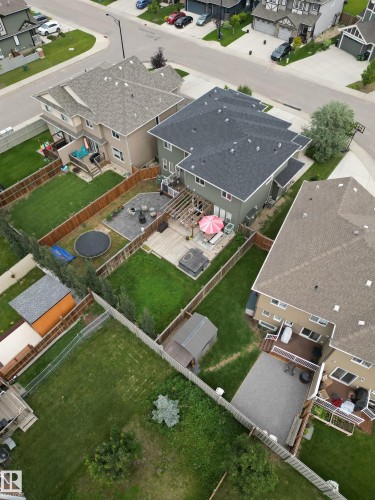 Expansive backyard featuring a green lawn, wood fencing, and a built-in deck with a pergola - 8916 217 Street, Edmonton, AB 