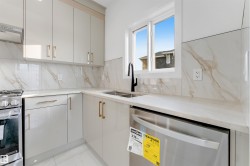 Contemporary kitchen featuring light-toned cabinetry with gold-toned hardware, a stainless steel gas range, and a stainless steel dishwasher - 