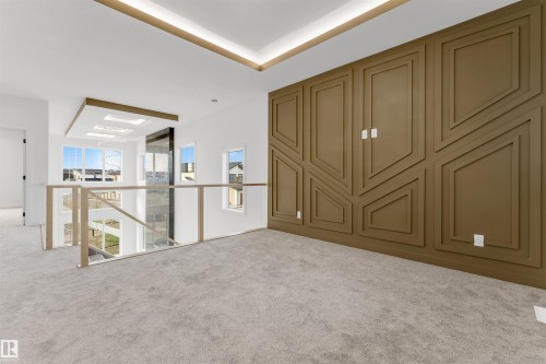 Upper-level landing featuring a custom accent wall with geometric paneling, light gray carpeting, and a glass-paneled railing system with light wood-finish posts - 1536 64 Ave, Rural Leduc County, AB 