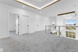 Upper-level landing featuring light gray carpet flooring, multiple white paneled doors with black hardware, and a glass-paneled railing overlooking an expansive window wall - 