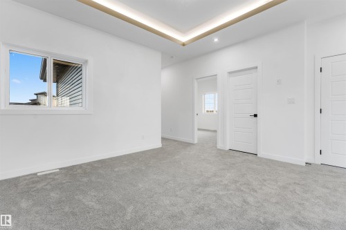 Spacious room featuring light gray carpet flooring, a white trim window, and multiple panel doors with matte black hardware - 1536 64 Ave, Rural Leduc County, AB 