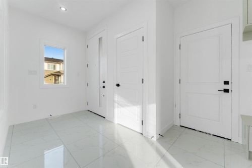Entryway featuring large format white tile flooring, recessed lighting, and a window with white trim - 1536 64 Ave, Rural Leduc County, AB 