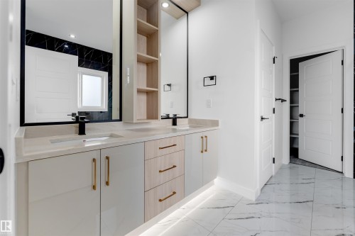Dual sink vanity with light wood-finish and white cabinetry, integrated under-cabinet lighting, and gold-finish hardware - 1536 64 Ave, Rural Leduc County, AB 