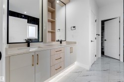Dual sink vanity with light wood-finish and white cabinetry, integrated under-cabinet lighting, and gold-finish hardware - 