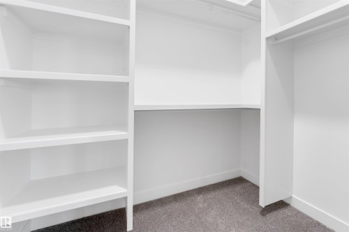 Built-in closet system featuring white shelving, hanging rod, and gray carpet - 1536 64 Ave, Rural Leduc County, AB 