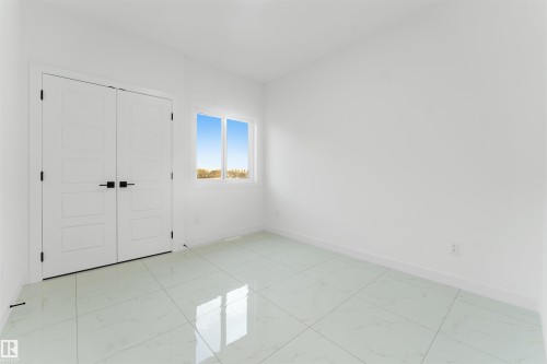 Spacious room featuring large format tile flooring, white walls, and a bright window - 1536 64 Ave, Rural Leduc County, AB 