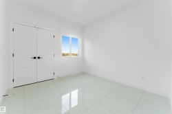Spacious room featuring large format tile flooring, white walls, and a bright window - 