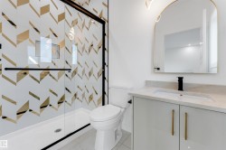 Shower enclosure featuring a custom tile surround with a geometric pattern and a black-framed glass door - 