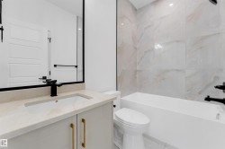 Bathroom featuring a modern vanity with light-toned countertop, built-in rectangular sink, and matte black faucet - 