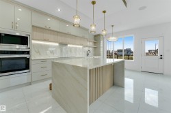 Modern kitchen featuring a waterfall island with slatted wood detailing, integrated stainless steel appliances, marble-effect slab backsplash, glossy white cabinetry, and polished tile flooring - 