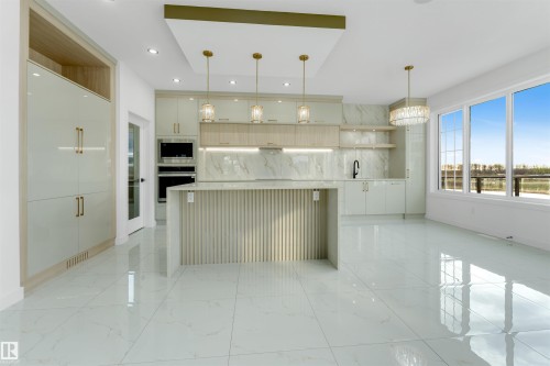 Spacious kitchen featuring large format polished tile flooring, a multi-pane window, built-in double ovens, and a kitchen island with a slatted base - 1536 64 Ave, Rural Leduc County, AB 