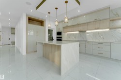 Modern kitchen featuring a large central island with a slatted wood-finish panel, integrated appliances, and a light-toned countertop - 