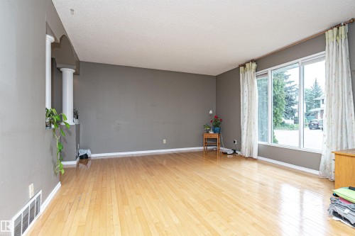 Living area featuring light wood-finish flooring, neutral gray walls, and white baseboards - 11512 24 Avenue, Edmonton, AB 