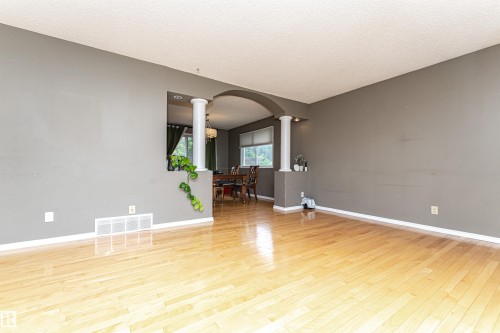 Spacious interior featuring wood-finish flooring and a neutral wall color - 11512 24 Avenue, Edmonton, AB 