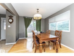 Bright dining area featuring hardwood flooring, a contemporary chandelier, a large window, and a sliding glass door providing exterior access - 