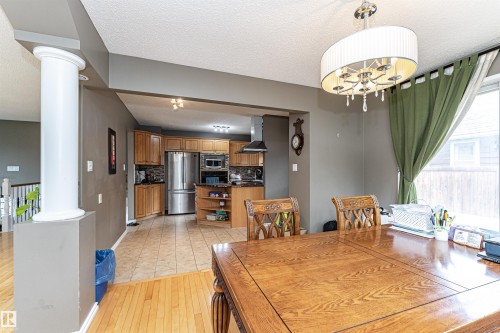 Open-concept living area with hardwood flooring, a decorative column, and an elegant drum chandelier - 11512 24 Avenue, Edmonton, AB 