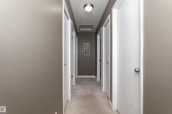 Interior hallway featuring neutral tone painted walls and textured carpeting - 