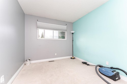 Bright room featuring light-colored carpeting, a window with a roller shade, and white baseboards - 11512 24 Avenue, Edmonton, AB 