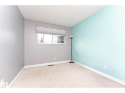 Room featuring plush carpet flooring, white baseboards, and a window with a roller blind - 