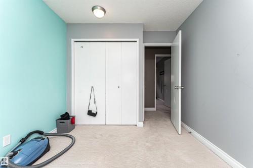 Room featuring light-colored carpet, a ceiling-mounted light fixture, white bi-fold closet doors, and white baseboards - 11512 24 Avenue, Edmonton, AB 