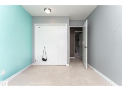 Interior space featuring light-toned patterned carpeting, white baseboards, and a bi-fold closet door - 