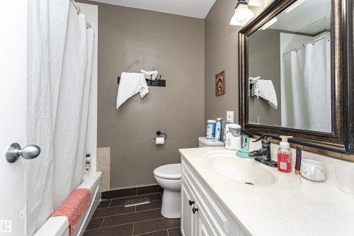 Bathroom featuring a white vanity with integrated sink, a framed mirror, and a full bathtub with shower - 11512 24 Avenue, Edmonton, AB 