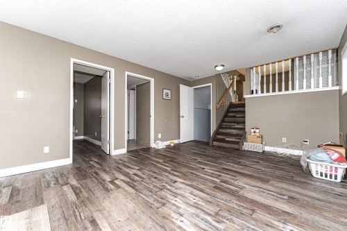 Spacious room featuring wood-finish flooring, neutral-toned walls, and white trim - 11512 24 Avenue, Edmonton, AB 