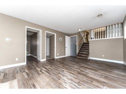 Spacious room featuring wood-finish flooring, neutral-toned walls, and white baseboards - 