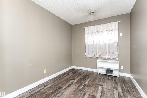 Neutral-toned room featuring wood-finish flooring - 11512 24 Avenue, Edmonton, AB 