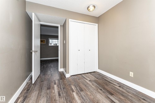 Room featuring wood-finish flooring, neutral wall paint, and a built-in closet with bifold doors - 11512 24 Avenue, Edmonton, AB 