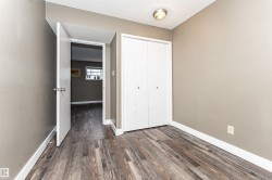 Room featuring wood-finish flooring, neutral wall paint, and a built-in closet with bifold doors - 