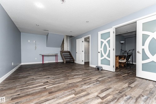 Spacious room featuring wood-finish flooring, light blue walls, and white baseboards - 11512 24 Avenue, Edmonton, AB 