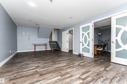 Spacious room featuring wood-finish flooring, light blue walls, and white baseboards - 