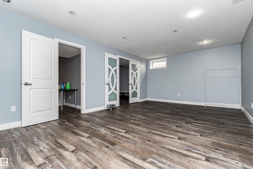 Spacious room featuring wood-finish flooring, light blue walls, and recessed lighting - 11512 24 Avenue, Edmonton, AB 