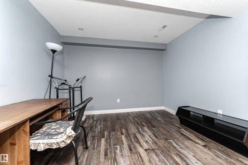 Room featuring light blue walls, white trim, and wood-finish flooring - 11512 24 Avenue, Edmonton, AB 