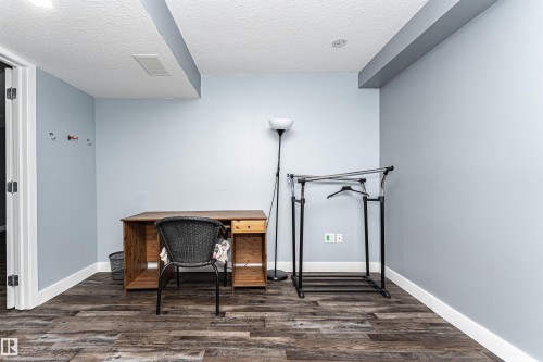 Spacious room featuring wood-finish flooring, white baseboards, light blue walls, and a white textured ceiling - 11512 24 Avenue, Edmonton, AB 