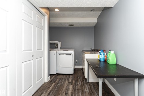 Dedicated laundry area featuring wood-finish flooring and grey walls - 11512 24 Avenue, Edmonton, AB 