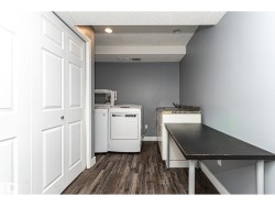 Dedicated laundry area featuring wood-finish flooring, a built-in countertop with an integrated sink, and white bi-fold closet doors - 