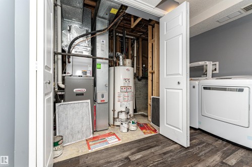 Dedicated utility area featuring a furnace, hot water heater, and washer/dryer hookups - 11512 24 Avenue, Edmonton, AB 