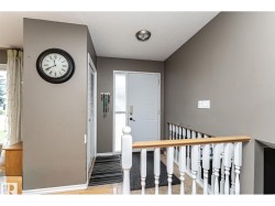 Entryway featuring a white paneled door with sidelight, tile flooring, and a white wood baluster railing with a natural wood-finish handrail - 