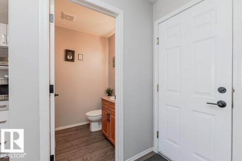 Entryway presenting a paneled white door with matte black hardware and a view into a powder room - 1816 36 Avenue, Edmonton, AB 