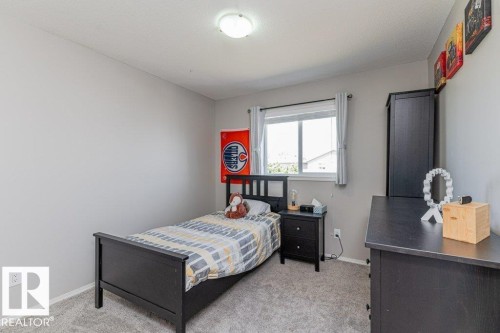 Neutral-toned bedroom featuring a double-paned window with curtain rod, light gray carpeting, and a flush-mount ceiling light fixture - 1816 36 Avenue, Edmonton, AB 