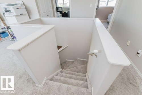 Staircase featuring light-colored carpeted treads, white painted risers, and white painted balustrades - 1816 36 Avenue, Edmonton, AB 
