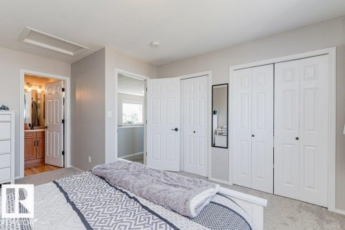 Bedroom featuring soft gray wall paint, light-toned carpet flooring, white bi-fold closet doors, and white interior doors - 1816 36 Avenue, Edmonton, AB 