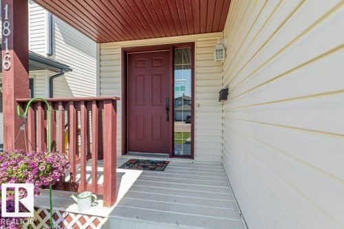Inviting front entry featuring a rich burgundy front door with a full-length sidelight, a coordinating porch ceiling, and a white siding exterior - 1816 36 Avenue, Edmonton, AB 