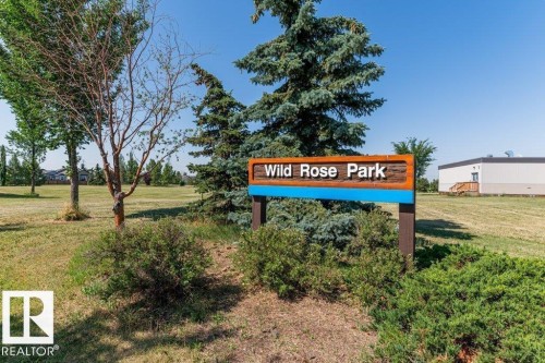Wild Rose Park signage with a manicured grassy area, mature trees, and shrubs - 1816 36 Avenue, Edmonton, AB 