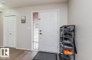 Entryway featuring a paneled door with a sidelight, wood-finish flooring, light grey painted walls, and a bi-fold closet door - 1816 36 Avenue, Edmonton, AB 