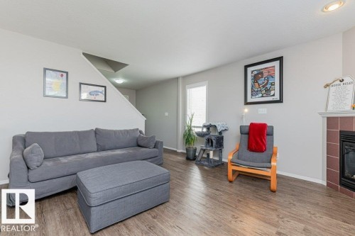 Living area featuring wood-finish flooring, light grey painted walls, and a fireplace with a tiled surround - 1816 36 Avenue, Edmonton, AB 
